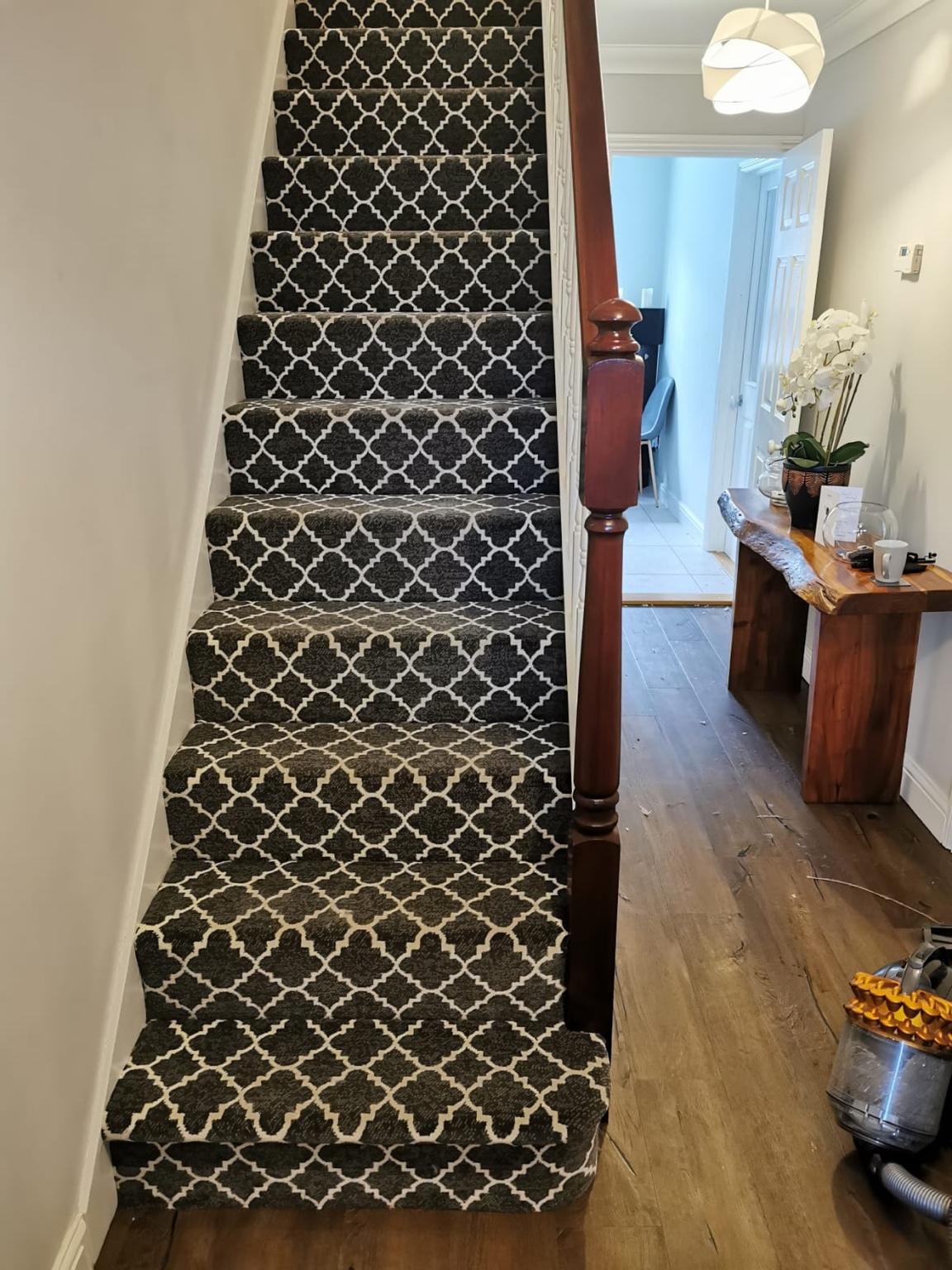Patterned carpet fitted to a straight flight of stairs, the pattern kept square and centred from one tread to the next