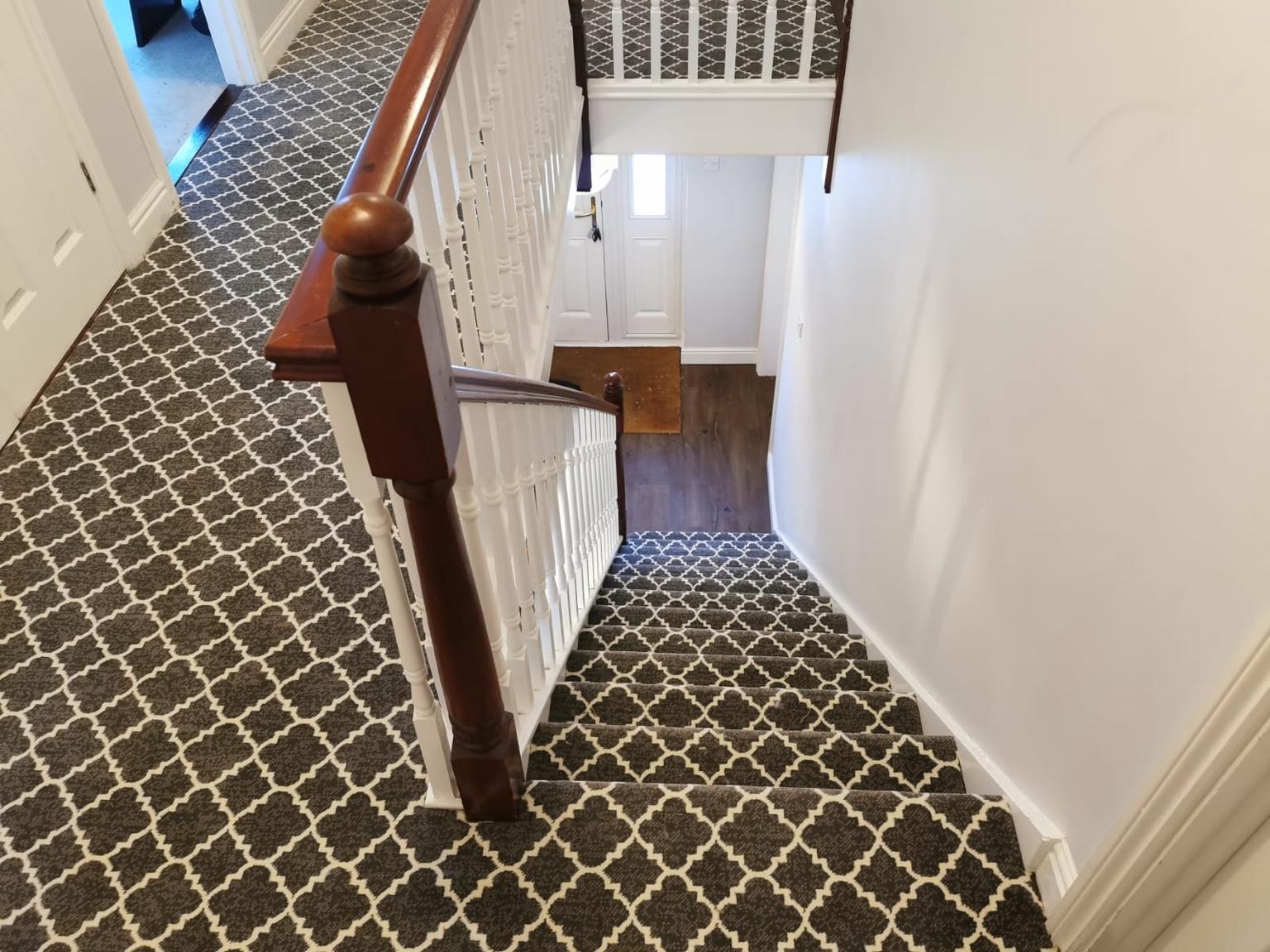 Patterned carpet seen from a landing, running along the landing and down the flight to the hall below