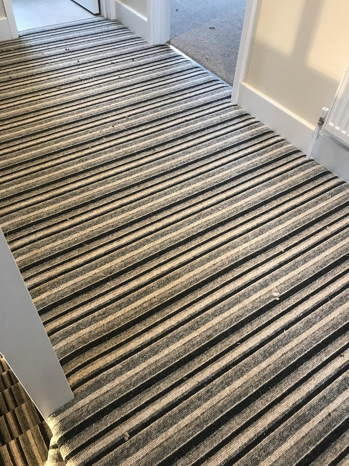 Striped carpet fitted across a landing, running through a doorway and up to the head of the stairs