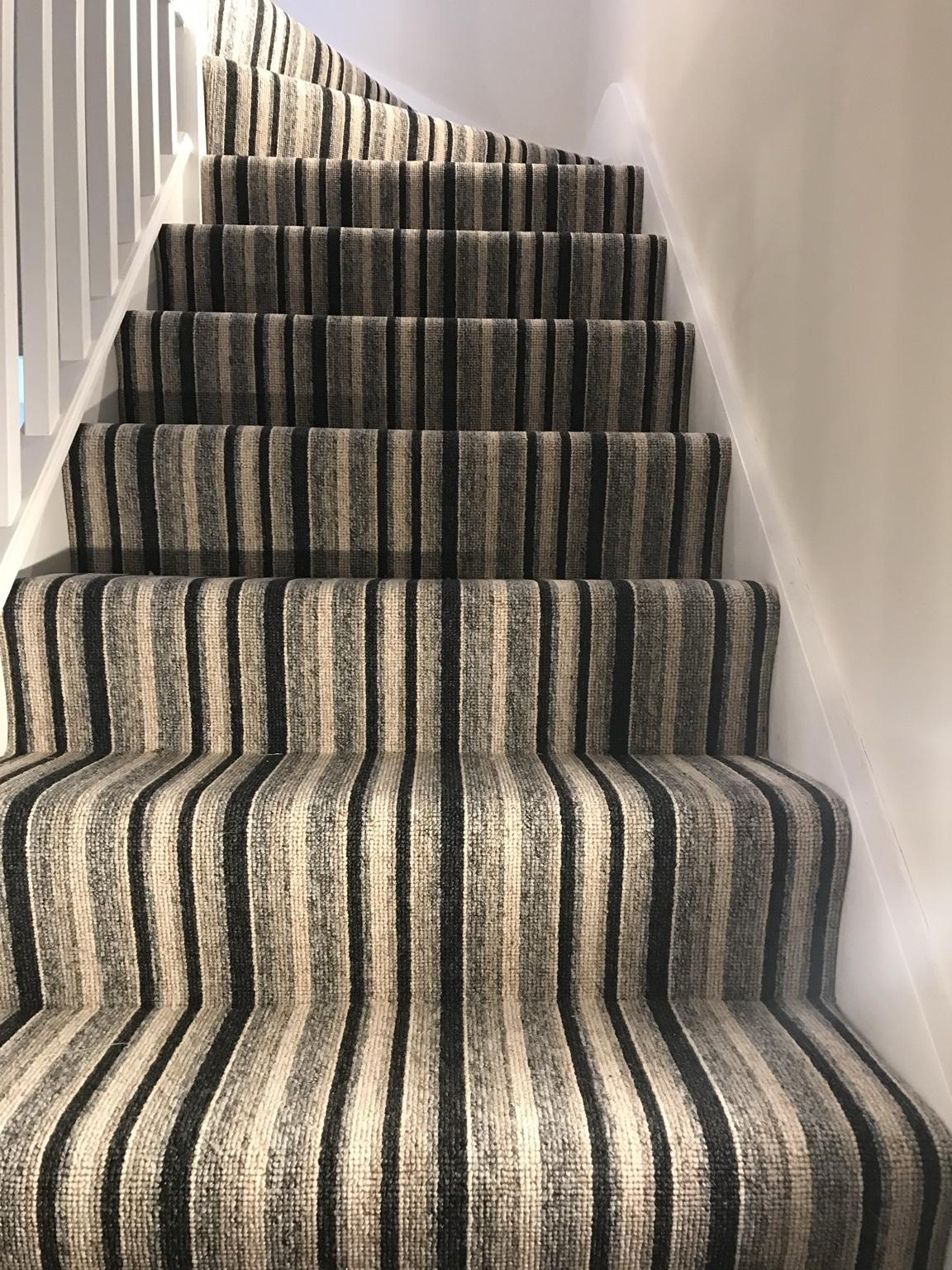 Striped carpet fitted to a staircase, the stripes running straight up each tread and turning with the stairs at the top