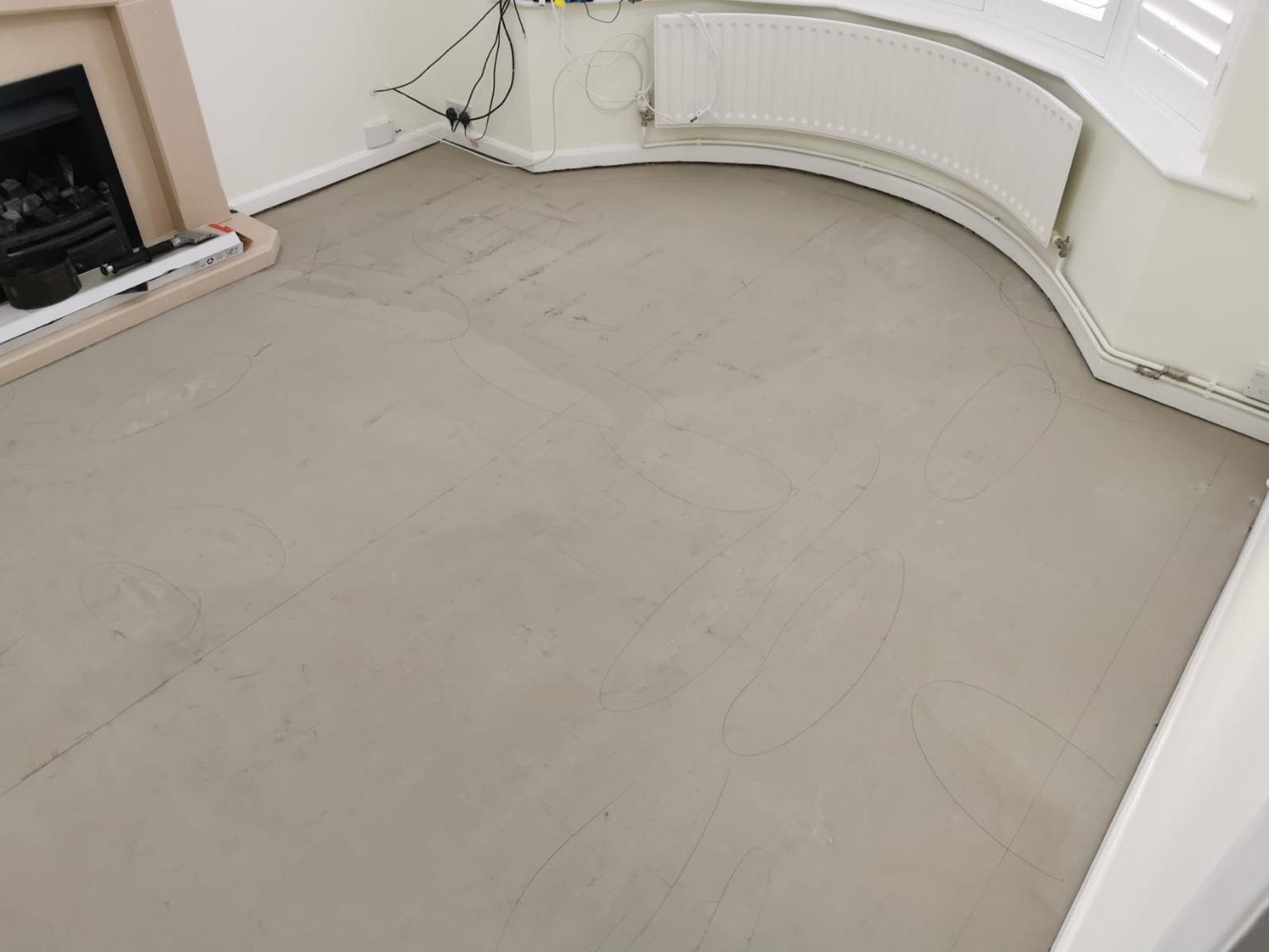 The prepared subfloor marked out by hand, the setting-out lines following the curve of the bay window