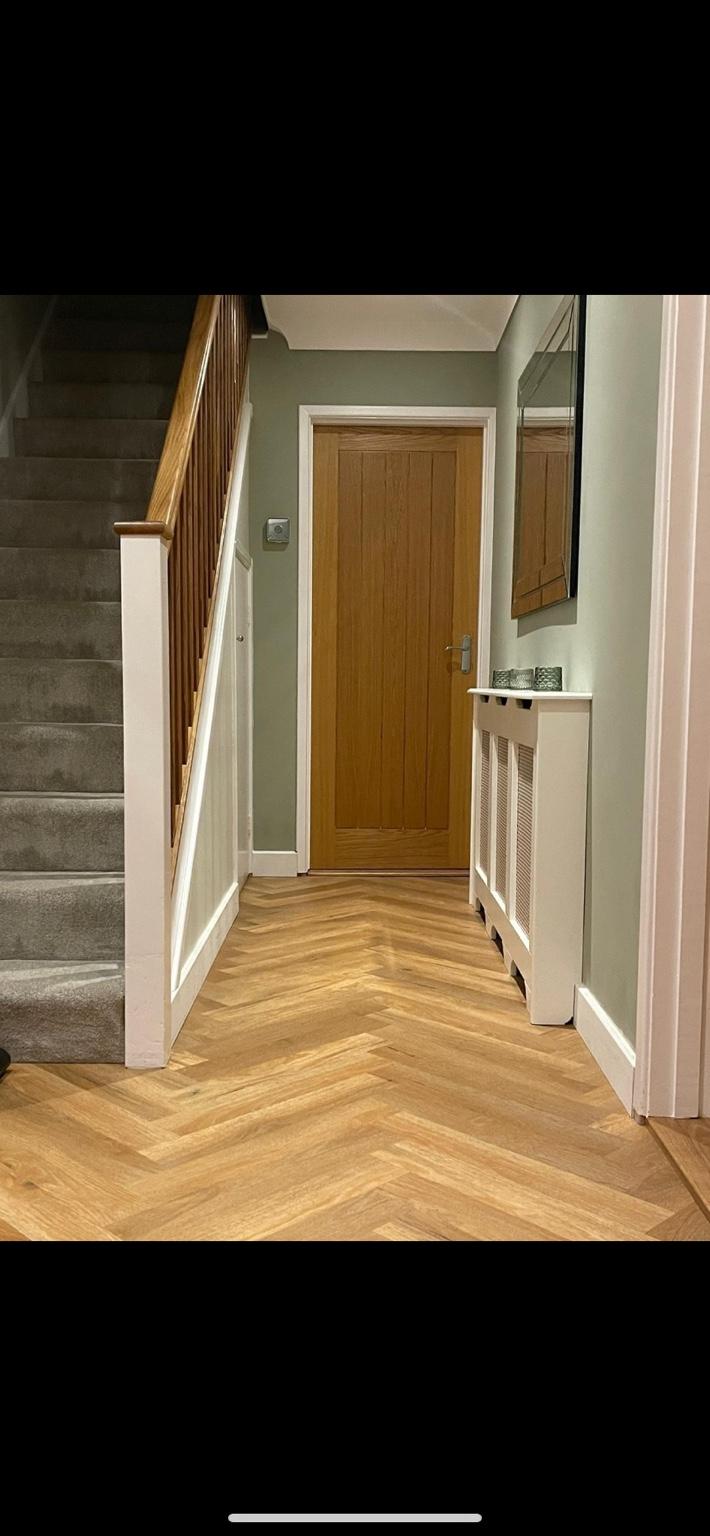 Herringbone flooring in a hallway with carpet fitted to the stairs alongside it, both in the same house