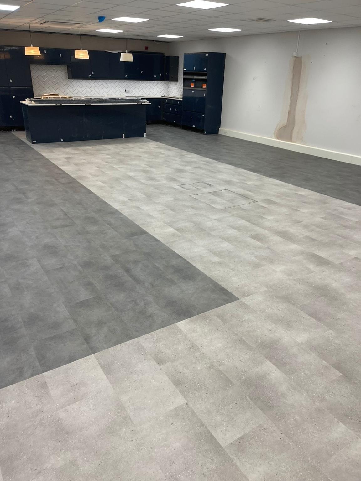 The finished vinyl floor looking towards the counter, the darker grey run meeting the lighter speckled area along a clean straight join